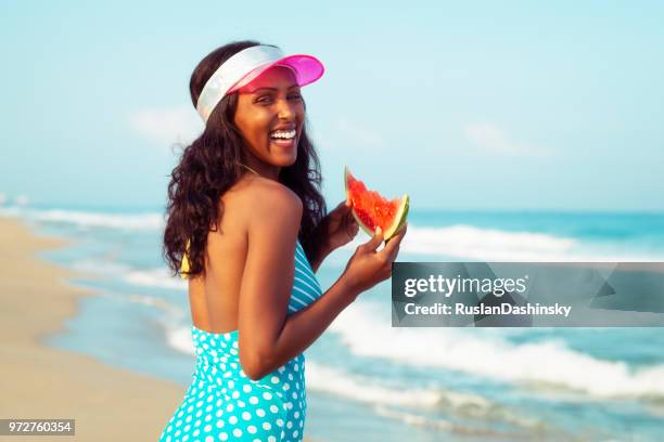 beautiful young woman eating slice of fresh watermelon on the sea beach. - ethiopian models women stock pictures, royalty-free photos & images