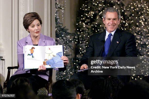 First Lady Laura Bush reads "Take a Mouse to the Movies" to school children in the East Room of the White House as President George W. Bush listens...