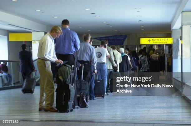 Long lines of people wait at LaGuardia Airport to pass through the carry-on baggage scanners and metal detectors, reflecting the increased...