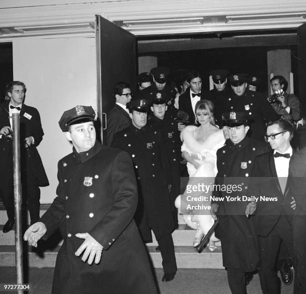 Brigitte Bardot and her boyfriend, Bob Zaguri , leave the Astor under heavy police escort. Her white coat became sullied while exiting through...