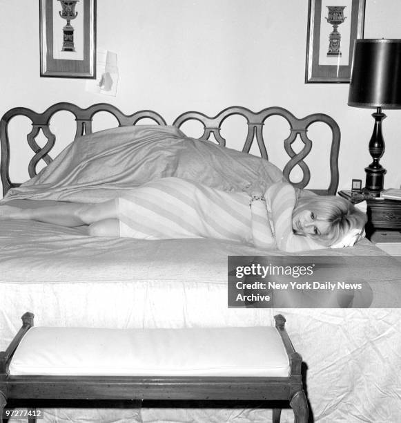 Brigitte Bardot takes respite on her bed at the Plaza Hotel from her busy schedule before doctor ordered dark glasses to protect her right eye,...