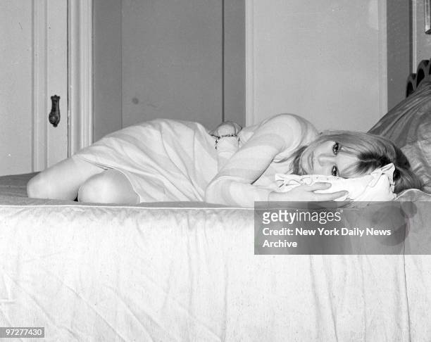 Brigitte Bardot takes respite on her bed at the Plaza Hotel from her busy schedule before doctor ordered dark glasses to protect her right eye,...