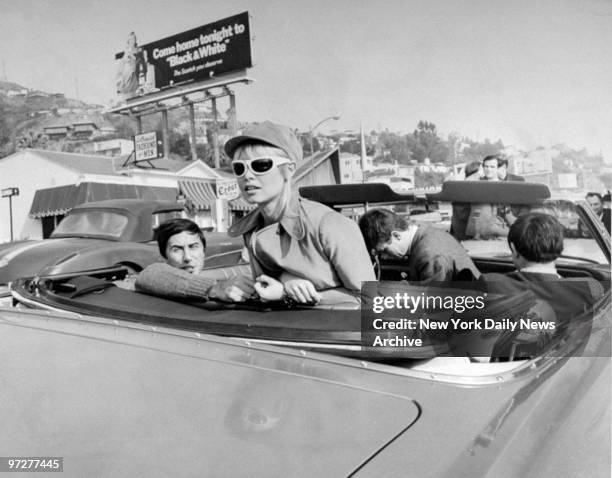 Brigitte Bardot tours Hollywood along Sunset Strip in the back of a convertible.