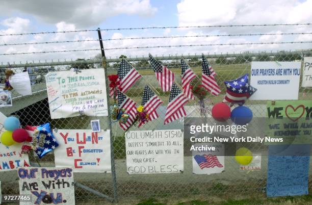 Flags and messages are attached to a fence outside the Johnson Space Center in Houston in memory of the seven astronauts who died yesterday in the...