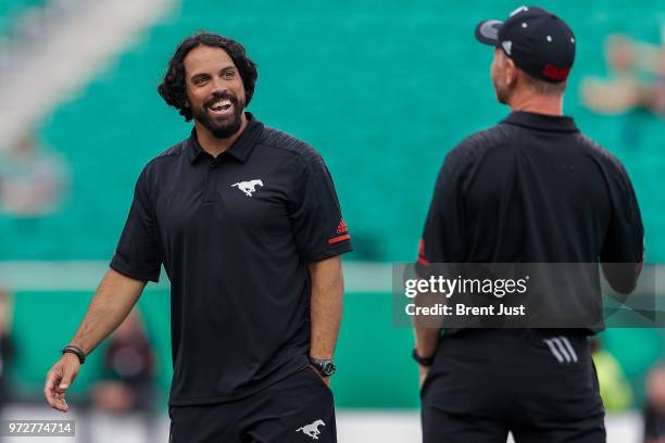 Calgary Stampeders special teams coordinator Mark Kilam talks with head coach Dave Dickenson on the field during pregame warmup before the preseason...