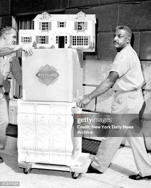 Jacqueline Kennedy and children move into new apartment at 1040 Fifth Avenue, New York City. Moving men wheel doll house and furnishings to delivery...