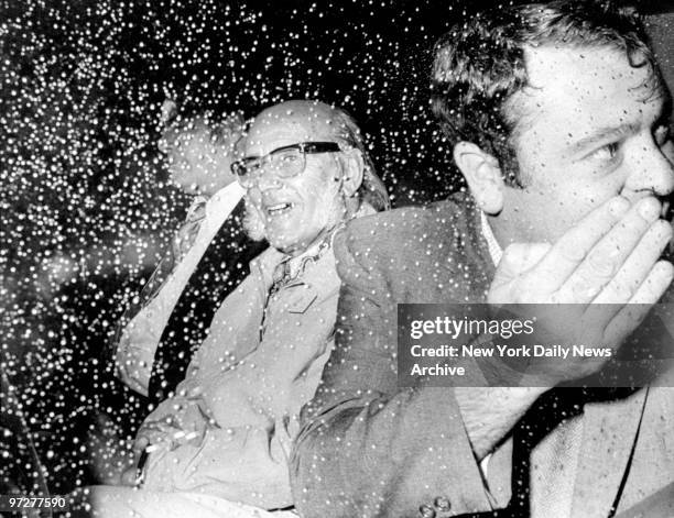 Flanked by federal agents, Auguste Joseph Ricord smiles through the rain-dotted window of the limousine at Kennedy Airport.