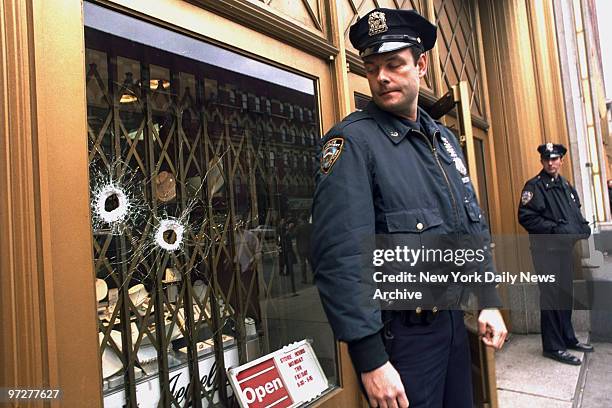 The front window of a jewelry store at 111 8th Ave. Is riddled with bullet holes after would-be robbers allegedly tried to shoot out the window with...