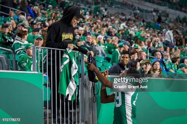 Duron Carter of the Saskatchewan Roughriders signs an autograph for a fan during the preseason game between the Calgary Stampeders and Saskatchewan...