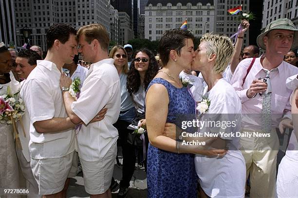 The grooms wear white, and so does one of the brides, at a same-sex wedding ceremony before the start of the 32nd annual Gay Pride Parade down Fifth...