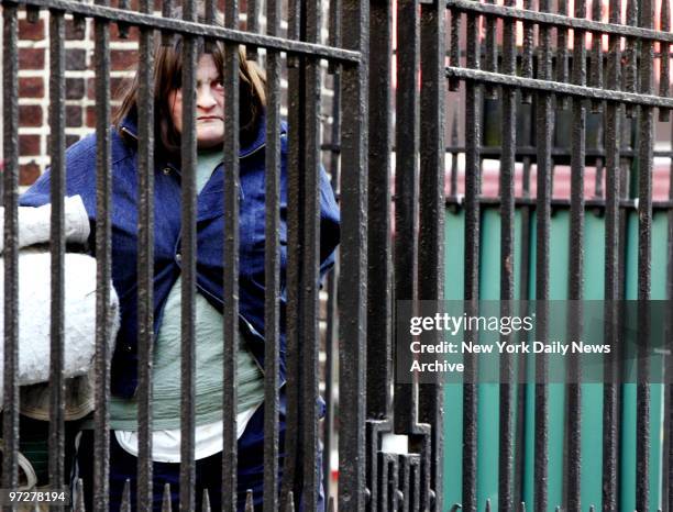 Lorraine House, who is homeless, looks out through the fence in Lieutenant Petrosino Square Park, across from The Falls restaurant and bar, where she...