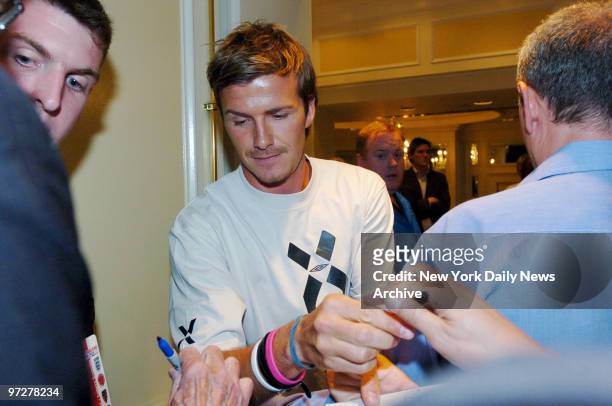 British soccer star David Beckham signs autographs for fans during a news conference at the InterContinental The Barclay New York hotel on E. 48th...
