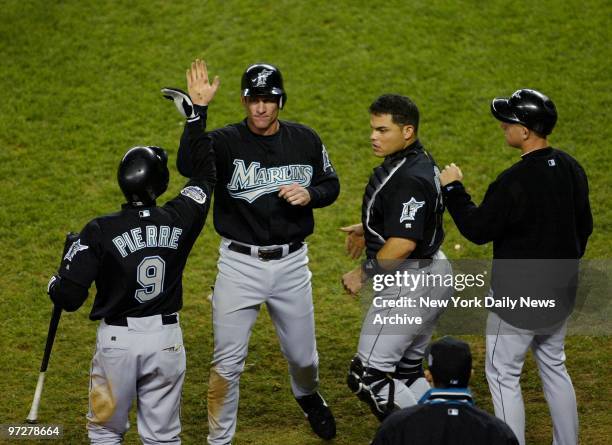 Florida Marlins' Jeff Conine is congratulated by Juan Pierre and catcher Ivan Rodriguez after he scored on a sacrifice fly in the sixth inning of...