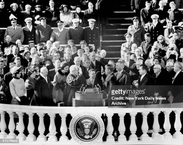 The Inaugural's most solemn moment occurs as Earl Warren, Chief Justice of United States, administers oath of office to John Fitzgerald Kennedy,...