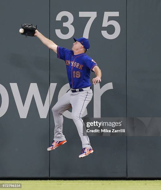 Right fielder Jay Bruce of the New York Mets jumps and stretches but does not catch a double hit by right fielder Nick Markakis of the Atlanta Braves...
