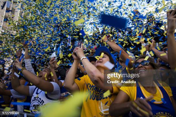 Fans cheer along the parade route as confetti flies while Klay Thompson and Zaza Puchulia of the Golden State Warriors pass by during the Golden...