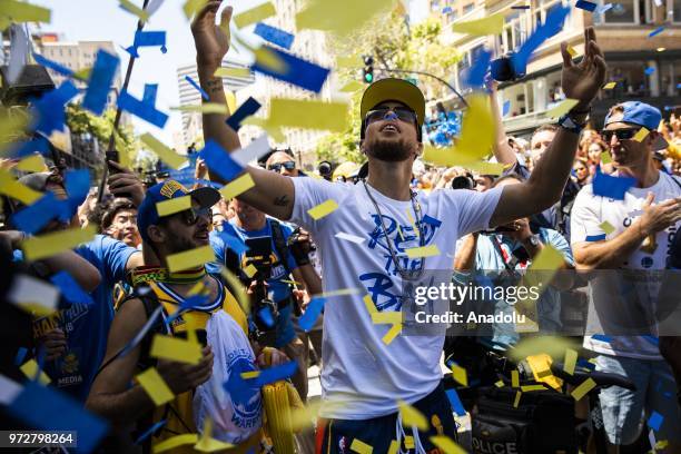 Stephen Curry of the Golden State Warriors delights in falling confetti as he interacts with fans along the parade route during the the Golden State...