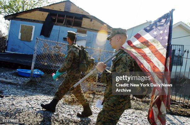 Cpl. Karl Krebsbach carries a tattered and muddied American flag he found as he and other Marines from Camp Lejeune, N.C., patrol a Lower Ninth Ward...