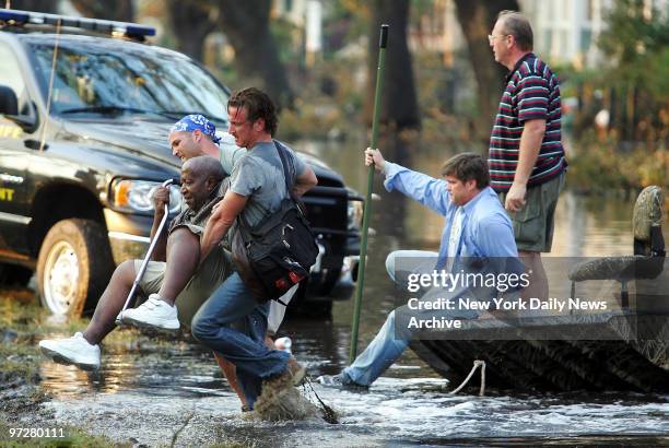 Sean Penn helps an elderly man stranded by Hurricane Katrina through the floodwaters to safety on Napoleon St. In New Orleans. The Oscar-winning...