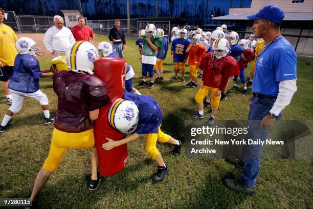 The Lightning Quick Blue Tigers' coach Mark Kidd directs his players through a tackling drill during practice on their newly-repaired athletic fields...