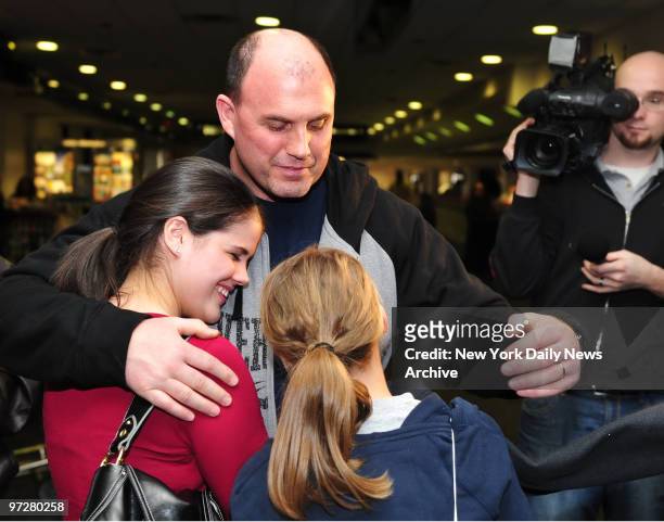 Crash Survivor Dave Sanderson hugs his daughters Chelsey Sanderson and Courtney Sanderson at the Charlotte-Douglas international airport where...