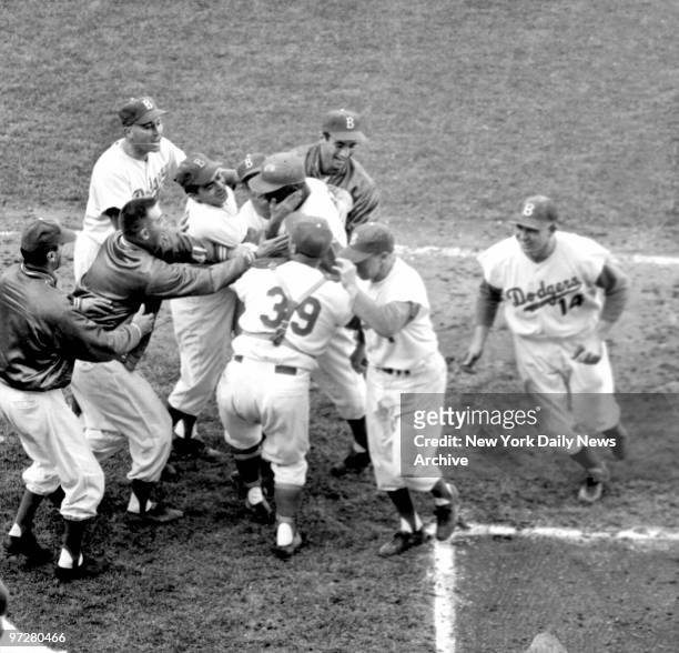 Crew-cut Clem Labine reaches through circle of jubilant teammates to embrace Jackie Robinson after Jackie bashed one over Slaughter's leaping grasp...