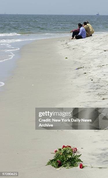 Flowers lie on the beach at Far Rockaway, Queens, as family members keep warch while search continues for two sisters who drowned when they were...