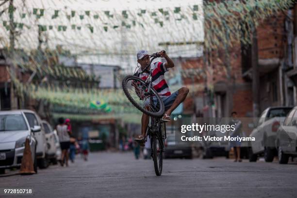 Boys pedal cycling in streets adorned with Brazilian flags in celebration of the 2018 World Cup in Russia. Brazil plays to be the champion for the...