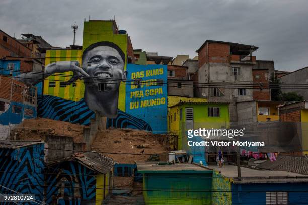 Children play soccer in front of the graffiti mural of the striker of the Brazilian soccer team Gabriel Jesus on June 12, 2018 in Sao Paulo, Brazil....