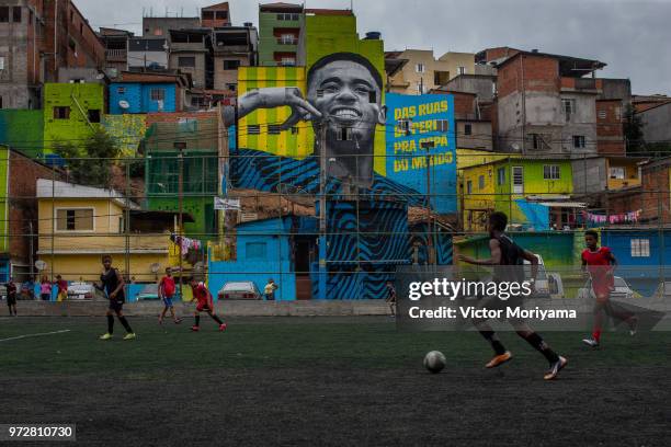 Children play soccer in front of the graffiti mural of the striker of the Brazilian soccer team Gabriel Jesus on June 12, 2018 in Sao Paulo, Brazil....