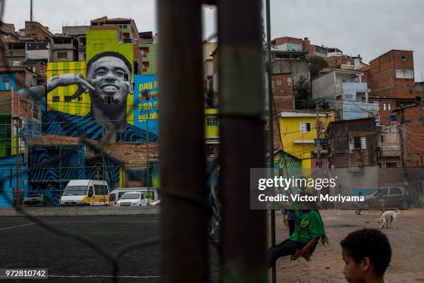 Children play soccer in front of the graffiti mural of the striker of the Brazilian soccer team Gabriel Jesus on June 12, 2018 in Sao Paulo, Brazil....