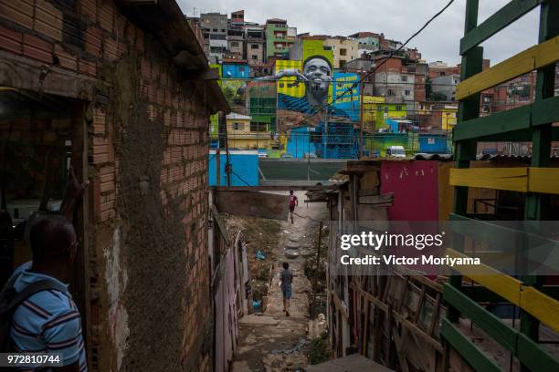 Children play soccer in front of the graffiti mural of the striker of the Brazilian soccer team Gabriel Jesus on June 12, 2018 in Sao Paulo, Brazil....