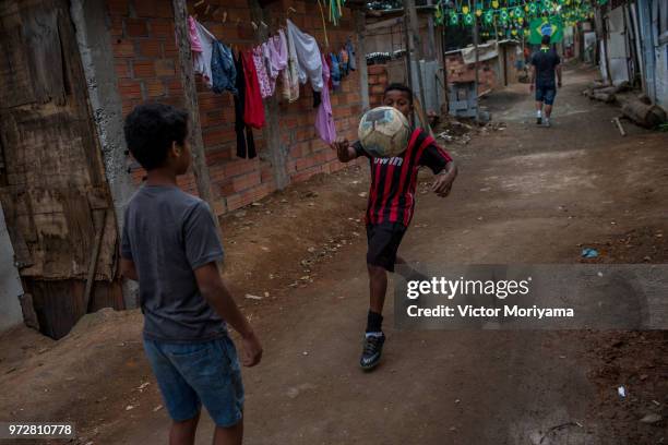 Children play soccer in front of the graffiti mural of the striker of the Brazilian soccer team Gabriel Jesus on June 12, 2018 in Sao Paulo, Brazil....