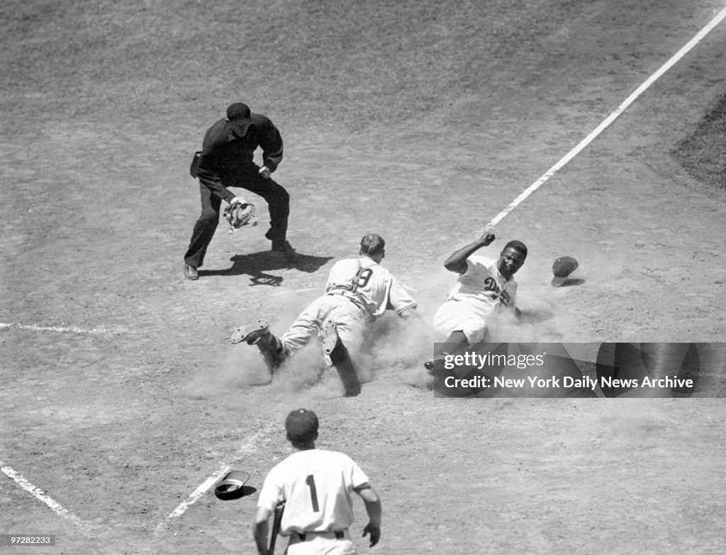Brooklyn Dodgers' Jackie Robinson kicks up dust as he slides