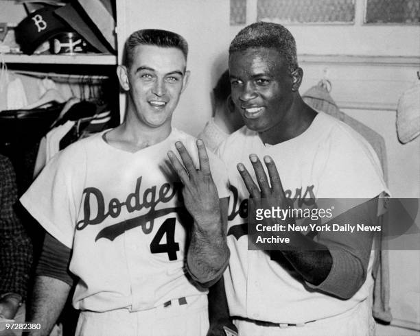 Brooklyn Dodgers' pitcher Clem Labine and Jackie Robinson in locker room during World Series. They're both holding up three fingers indicating the...
