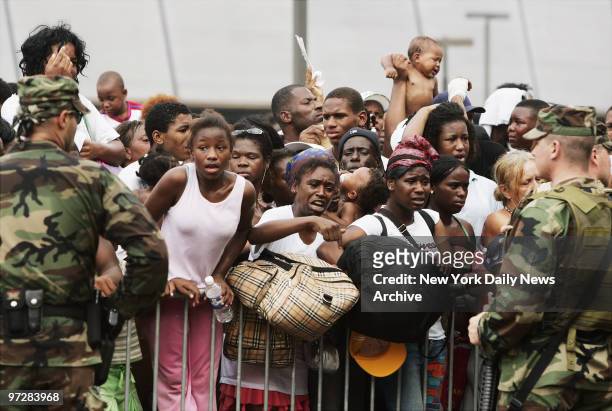 National Guardsmen stand watch at barricades outside the Superdome as emotional refugees driven from their homes by Hurricane Katrina await...