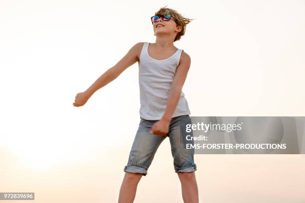 boy dances the fortnite floss move, aka swish shish dance, a on-trend dance inspired by the survival video game fortnite. - the floss dance stock pictures, royalty-free photos & images