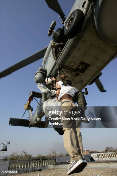 Navy Petty Officer Second Class Mike Basham airlifts a man to safety from the rooftop of a public school in New Orleans' flooded Ninth Ward. Military...