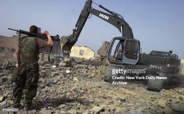 Navy Seabees demolish bombed-out buildings at Umm Qasr to get debris to use as landfill for a ferry landing in the harbor.The British army, in an...