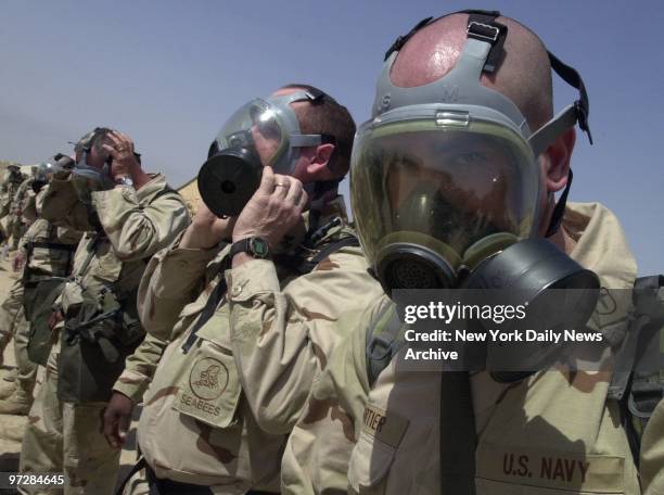 Navy Seabees go through a gas mask drill at Al Jaber Air Base in Kuwait. American troops and equipment are massed in Kuwait in readiness for a...