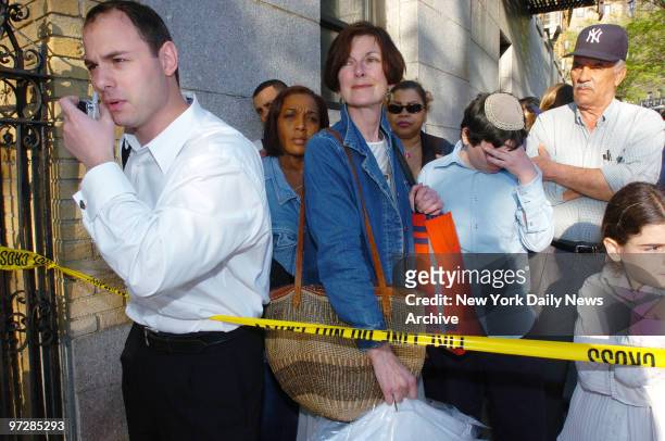 Neighborhood residents wait anxiously behind police tape after being temporarily barred from returning to their apartments following the collapse of...