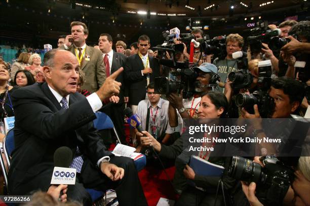 Former Mayor Rudy Giuliani talks to the media from his seat in the New York delegation on opening day of the Republican National Convention at...