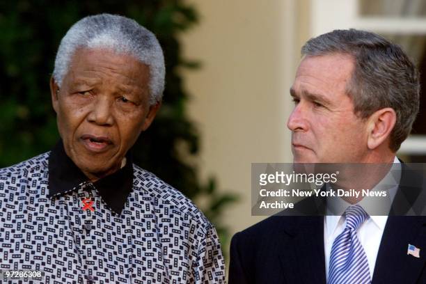 Nelson Mandela speaks to the press as President George W. Bush looks on during a press conference outside the Oval Office after their meeting. They...