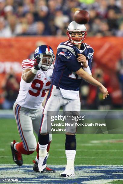 New England Patriots' quarterback Tom Brady passes the ball under pressure from New York Giants' defensive end Michael Strahan during the first...