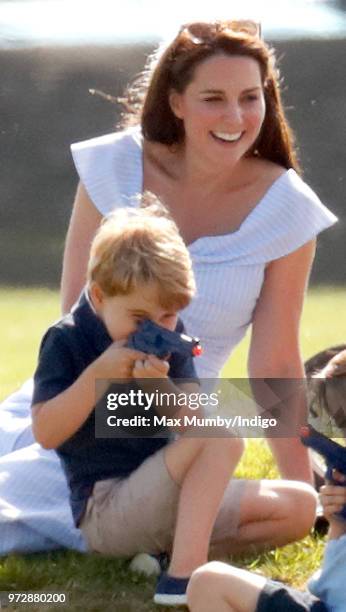 Catherine, Duchess of Cambridge looks on as Prince George of Cambridge plays with a toy gun whilst attending the Maserati Royal Charity Polo Trophy...