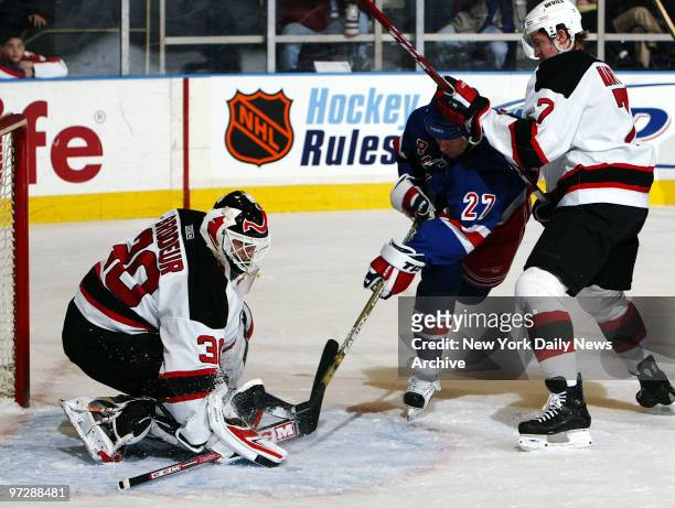 New Jersey Devils' goalie Martin Brodeur stuffs a shot by the New York Rangers' Alexei Kovalev as Devils' Paul Martin defends during the first period...