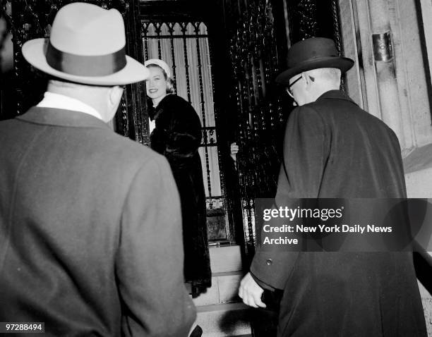 Grace Kelly looks back with a smile as she enters Cardinal Spellmans's Madison Ave. Residence for luncheon appointment. Following Grace are her...