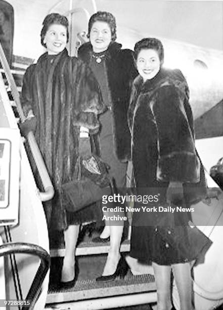 McGuire Sisters Christine, Phyllis and Dorothy standing on aircraft stairs.