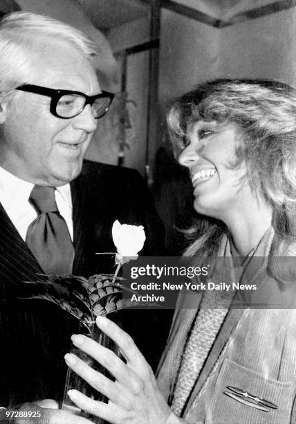 Carey Grant offers Farrah Fawcett a rose during party at Le Premier Restaurant to introduce Farrah to the Faberge fashion.