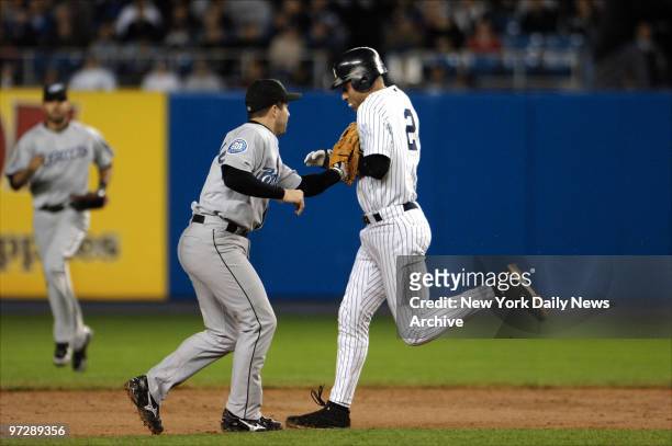 New York Yankees' Derek Jeter avoids the tag from Toronto Blue Jays' shortstop John McDonald long enough for Robinson Cano to score from third base...